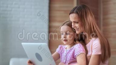 关爱的母亲拥抱小女儿说话，一起使用笔记本电脑。 4k龙红相机